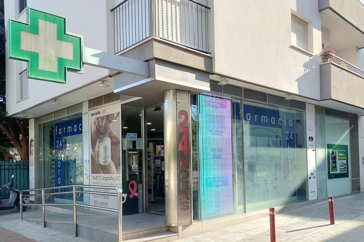 Fachada de Farmacia 24 Horas Lorca con su cruz verde encendida, en la Alameda de Ramón y Cajal